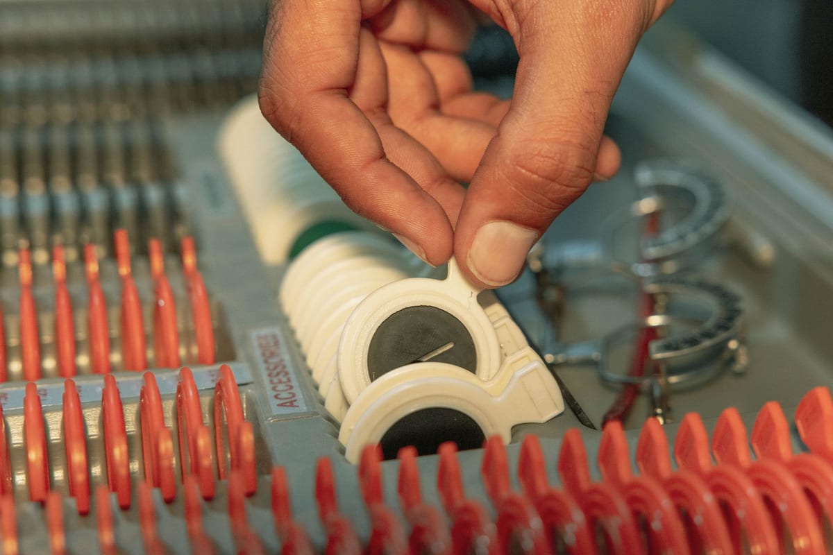 A hand lifting a single lens from a trial lens set